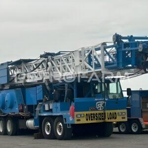 Vista de perfil lateral completo del camión carrier de Workover Rig Service King con letrero Oversized Load y mástil plegado